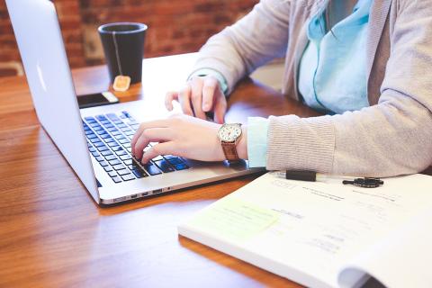 egy hölgy egy laptop billentyűzetén dolgozik